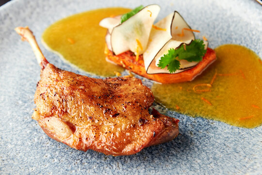 Duck leg with vegetable garnish of carrot and black radish.