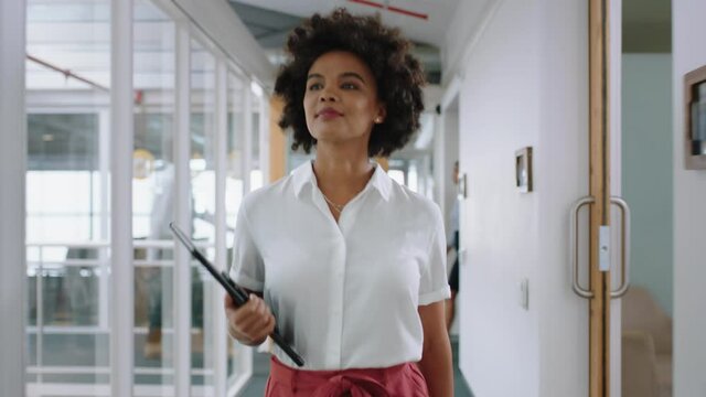 mixed race business woman smiling walking through office holding tablet computer enjoying successful career in corporate workplace 4k