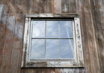 Window reflection in old weathered wood barn wall