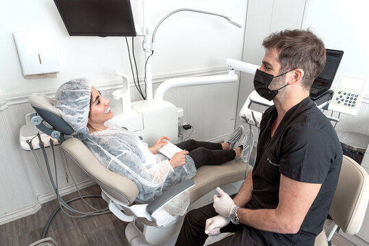 Dentista habla con su paciente mujer, explicando lo que va a hacer en su boca