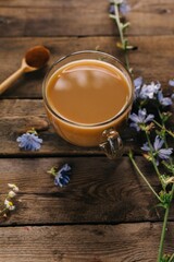 Glass mug with chicory drink on wooden background