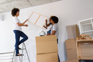 Happy playful African American family moving in new apartment, unpacking, moving stuff, purchase property concept