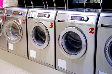 row of washing machines in public city self-service laundromat, clean linen concept, washing clothes, bachelor life