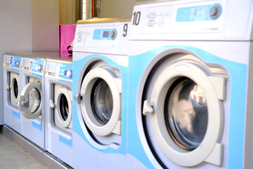 blurred photo of a row of washing machines in a public city self-service laundromat, concept of clean linen, washing clothes, bachelor life