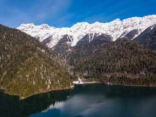Obraz premium Aerial view of mountain glacial lake Ritsa in Abkhazia at winter season. Rocky mountain peaks covered with snow. Beautiful mountain landscape from drone. Abkhazia.
