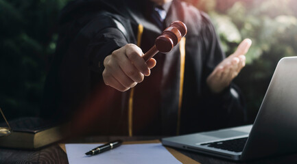 Justice and law concept.Male judge in a courtroom with the gavel, working with, computer and...