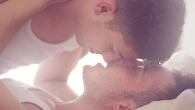 Romantic gay couple lying in bed, kissing and hugging. Men Couple in love. LGBT