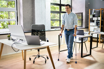 Worker With Crutches At Workplace Or Office