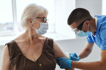 male doctor giving an injection to an elderly woman patient covid passport