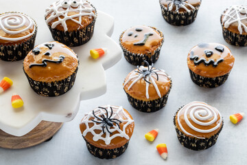 Many Halloween decorated cupcakes scattered about, against a light background.