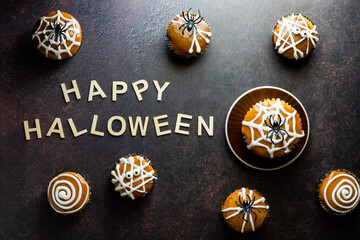 Several Halloween decorated cupcakes forming a border with the words Happy Halloween in the middle.