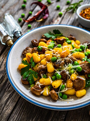 Gnocchi with fried white mushrooms, green peas, parmesan and parsley on wooden table
