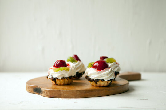 cupcakes with cottage cheese on vintage tray-tasty muffin with strawberry and kiwi on wooden plate