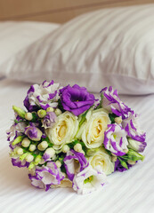 beautiful wedding bouquet of roses lying on white bedsheet