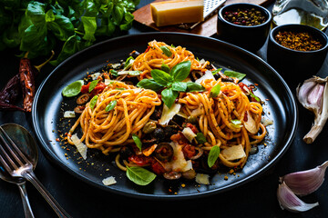 Pasta puttanesca with tomato sauce, anchovies, chilli, capers and olives on wooden table
