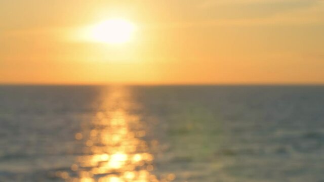 Defocused out of focus bokeh blurry sunset yellow golden color in Seaside, Santa Rosa Beach, Florida in panhandle gulf of mexico ocean with waves and reflection of sun path in water surface