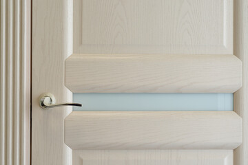 Beige curved handle on textured door with glass insert / interior