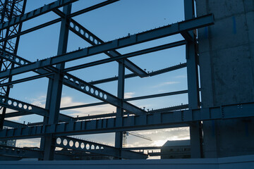 Construction steel framework in silhouette against blue sky.