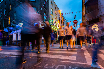 Legs and feet in motion blur as people crossing busy intersection at twilight