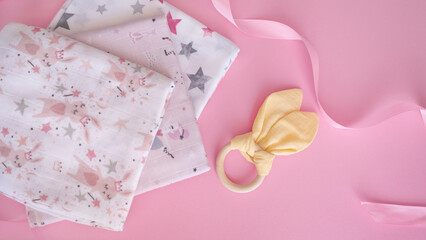 Set of cute napkins cloth for newborn girl with wooden textile toy on gently pink background. Bright accessories for baby. Birthday, childcare and maternity concept