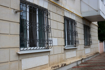 Windows barred with black metal bars on the white wall of the house