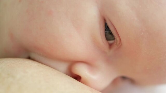 Video of an infant drinking milk. Macro shot of a small caucasian baby eating while on his mother&rsquo;s hands. Breast feeding. Child eating before an afternoon nap. Cinematic footage of brestfeeding.