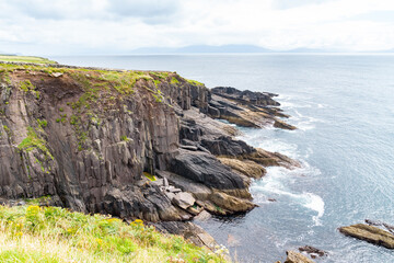 Steep dramatic coastal rock cliffs along Wild Atlantic Way tourist route.