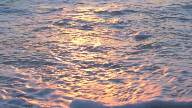 Sunset in Seaside, Santa Rosa Beach, Florida in panhandle with closeup of shore and gulf of mexico ocean waves and reflection of sun path in water surface