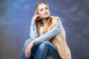 Fototapeta na wymiar elegant woman sits wearing blue jeans and fur vest