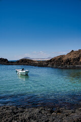 Fototapeta na wymiar Barca en aguas azules dentro del puerto de la Isla de Lobos, Fuerteventura. 