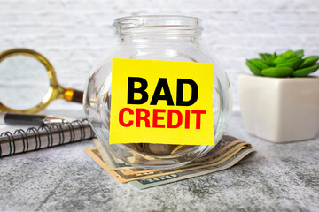 Some banknotes in a glass jar, with its lid near it, with the words, bad credit on it. Concept of unclaimed loans.