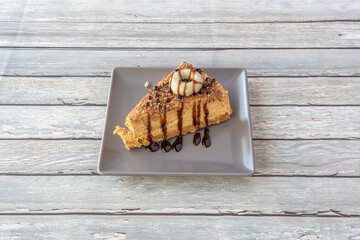 Delicious portion of dulce de leche cake with chocolate syrup, chopped almonds and mini white...
