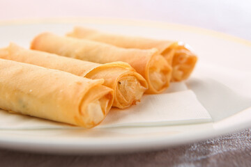 A bright background and four spring rolls on a white plate 밝은색 배경 그리고 흰색 접시에 담겨져 있는 춘권 4개