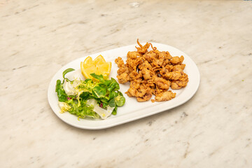 Squid battered with flour and egg, salad and lemon to garnish