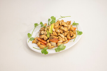 Tray of chicken with almonds and vegetables cooked in a wok in a Chinese restaurant with coriander and carrots