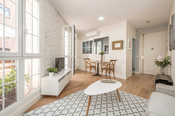 Nice living room with white exposed brick wall and large windows leading to the terrace of a...