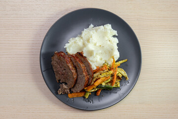 A plate of meatloaf with mashed potato and vegetables.