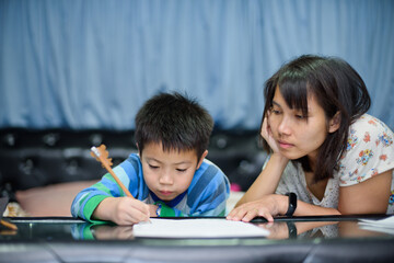 children boy doing homework with mother, kid write paper, family concept, learning time, student, back to school 
