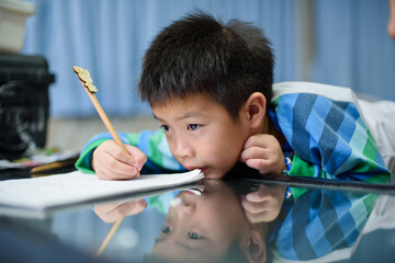 Asian boy doing homework on green screen, child writing paper,  education concept, back to school
