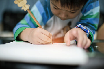 Asian boy doing homework on green screen, child writing paper,  education concept, back to school
