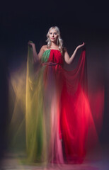 Young beautiful female model in colorful dress on black background