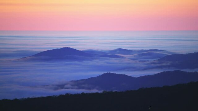 High angle aerial view above inversion clouds at sunrise morning in Wintergreen Resort, Virginia ski town with colorful sky, autumn fall trees in Blue Ridge mountains