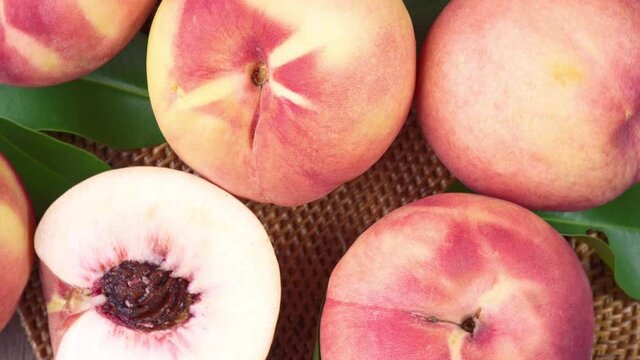 Top view Rotate Fresh peach with slices closeup, White peach on Bamboo mat on wooden table in garden.