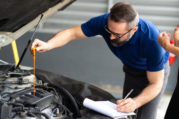 Fototapeta na wymiar Auto mechanic worker checking oil level in car engine. Car maintenance and auto service garage concept.