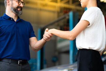 Expertise mechanic shaking hands with satisfied customer and working in automobile repair maintenance station garage. Satisfaction in service