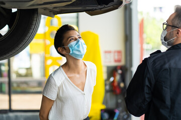 Mechanic man and woman customer wearing medical face mask protection coronavirus and check the car condition before delivery.