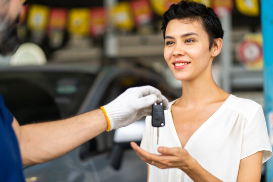 Middle Age Mechanic Man With Beard Gives The Car Key To Female Customer At Car Maintenance Station And Automobile Service Garage