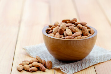 Almonds in brown bowl on wooden background