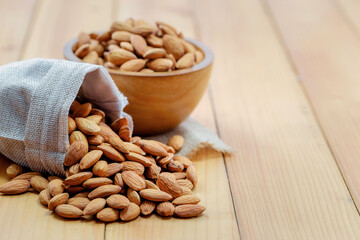 Almonds in brown bowl on wooden background