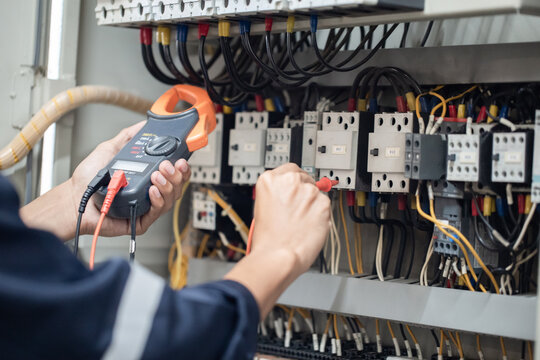 Electrician engineer work tester measuring voltage and current of power electric line in electrical cabinet control , concept check the operation of the electrical system .